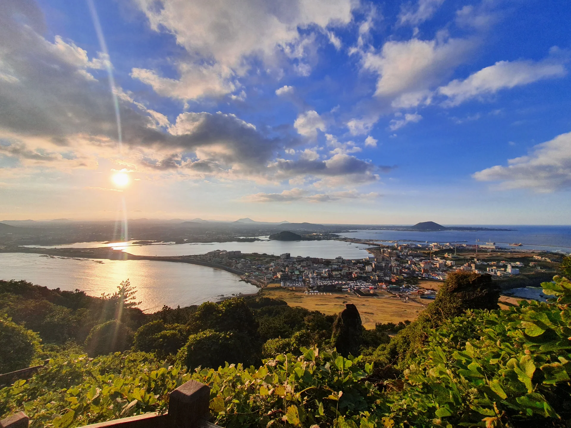 Paint your phone screen with the warm glow of a Korean sunset. These wallpapers capture golden hour at its most magical — amber light washing over temple rooftops, cotton-candy skies reflected in still rice paddies, and the Seoul skyline silhouetted against bands of pink, orange, and violet as the sun dips below the horizon.

Each image showcases a different face of the Korean evening: fishing boats returning to harbor under a fiery sky, lone hikers on ridgelines backlit by the last rays, and coastal cliffs glowing in warm light. These free aesthetic sunset wallpapers make the perfect phone background for anyone who wants a daily reminder of that peaceful, fleeting beauty between day and night., Jeju Island, Seongsan Ilchulbong — Free Korean aesthetic wallpaper