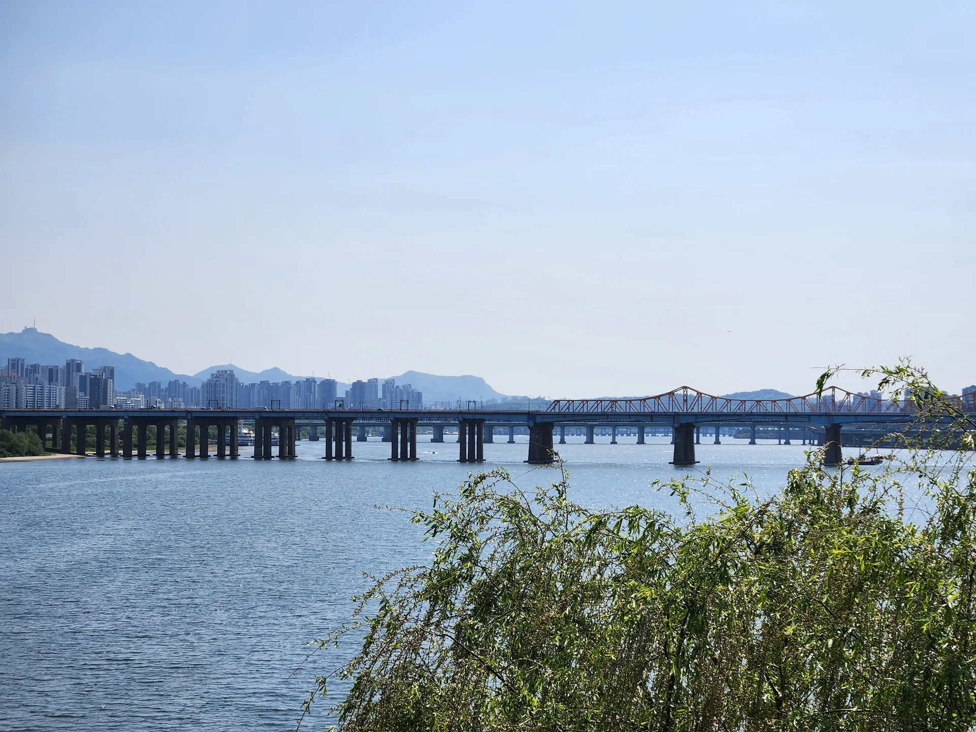 Bring the peaceful flow of Korea's waterways to your phone screen. These river wallpapers feature the iconic Han River cutting through Seoul's skyline, its surface mirroring city lights at dusk, as well as serene lakeside scenes from the countryside where mountains descend to meet still water and morning fog drifts across the surface.

From riverside cycling paths lined with cherry blossoms to dramatic reflections of autumn foliage in mountain streams, each image captures the calming presence of water in Korean landscapes. Waterfront pavilions, stone bridges arching over gentle currents, and lone boats floating in golden light are all waiting here. Download these free Korean river wallpapers for an aesthetic phone background full of tranquility., Gangbyeonbuk-ro, Seongsu 1(il)-ga 1(il)-dong, Seoul — Free Korean aesthetic wallpaper