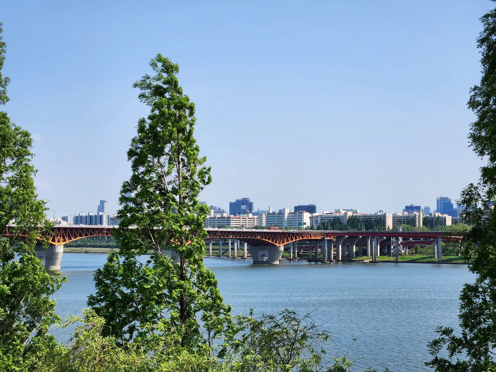 Bring the peaceful flow of Korea's waterways to your phone screen. These river wallpapers feature the iconic Han River cutting through Seoul's skyline, its surface mirroring city lights at dusk, as well as serene lakeside scenes from the countryside where mountains descend to meet still water and morning fog drifts across the surface.

From riverside cycling paths lined with cherry blossoms to dramatic reflections of autumn foliage in mountain streams, each image captures the calming presence of water in Korean landscapes. Waterfront pavilions, stone bridges arching over gentle currents, and lone boats floating in golden light are all waiting here. Download these free Korean river wallpapers for an aesthetic phone background full of tranquility., Gangbyeonbuk-ro, Seongsu 1(il)-ga 1(il)-dong, Seoul — Free Korean aesthetic wallpaper