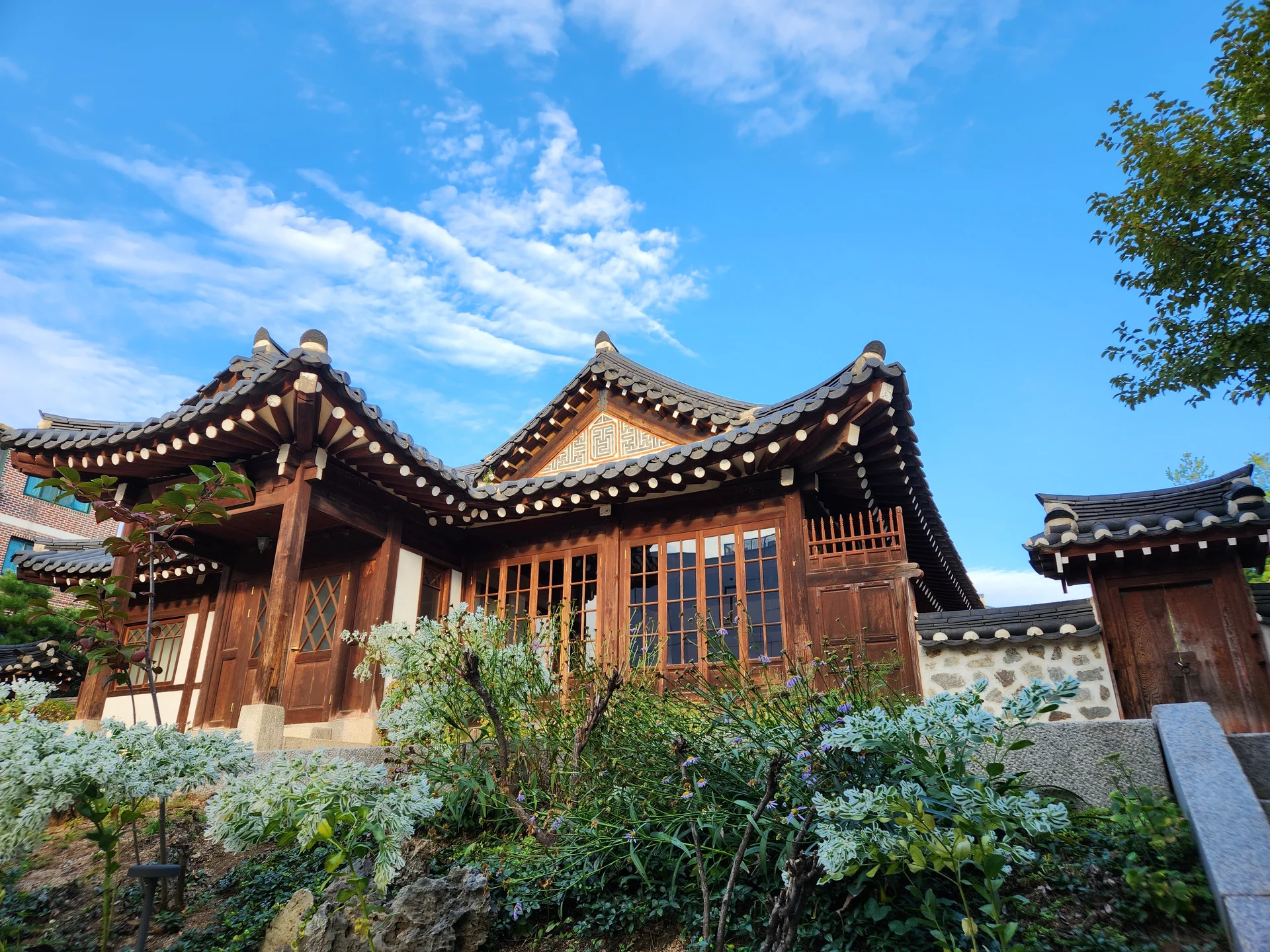 Adorn your phone with the timeless elegance of hanok, Korea's traditional wooden houses. These wallpapers showcase the graceful curved rooflines, hand-carved wooden lattice doors, and serene inner courtyards that have defined Korean residential architecture for centuries. Preserved hanok villages in Bukchon and Jeonju offer a living window into Korea's past.

Each image reveals the quiet beauty of these heritage homes — clay walls weathered to warm earth tones, dark timber frames contrasting with paper-screened windows, stone foundations meeting manicured courtyard gardens, and traditional eaves silhouetted against modern skylines. Download these free hanok wallpapers for an aesthetic phone background that celebrates the harmony between Korean tradition and contemporary life., Bukchon-ro, Gahoe-dong, Seoul — Free Korean aesthetic wallpaper