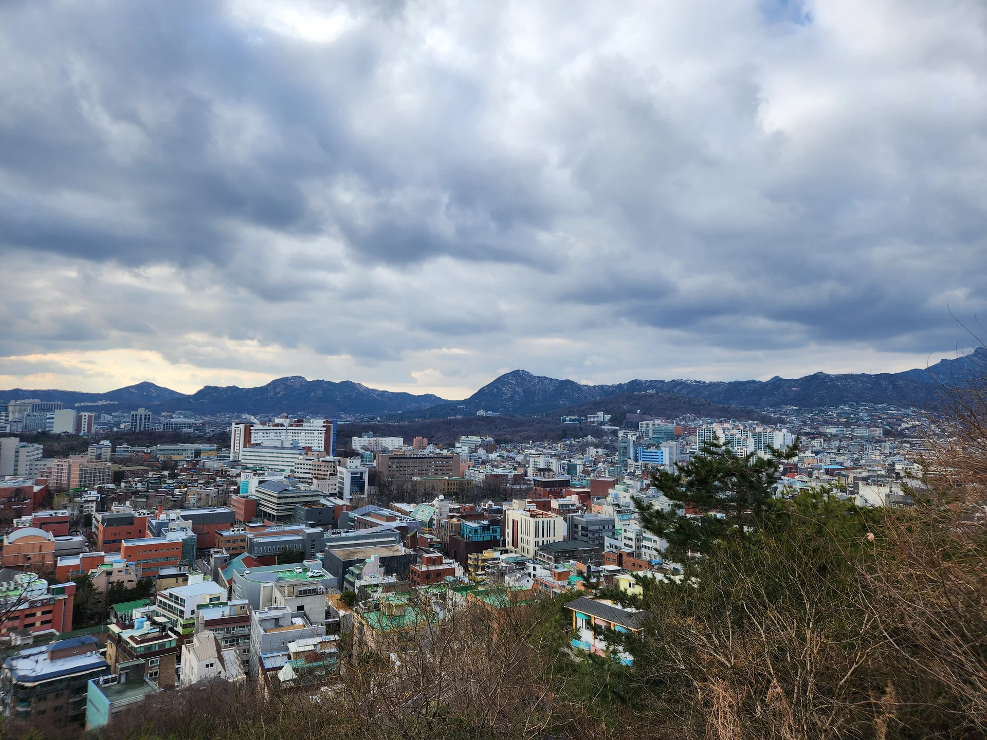 Experience the vibrant pulse of Korean city life through these dynamic street wallpapers. Bustling crosswalks in Myeongdong, colorful shop fronts in Hongdae, rain-slicked sidewalks reflecting neon signs, and everyday moments of commuters, street vendors, and cyclists moving through Seoul's urban rhythm — each image tells a story of a city constantly in motion.

Beyond Seoul, you'll find the charming streetscapes of Busan's hillside neighborhoods, the retro storefronts of Jeonju, and quiet residential lanes where laundry dries on balconies above parked scooters. These free Korean street wallpapers are perfect as an aesthetic phone background for anyone captivated by the raw energy and visual richness of Korean urban culture., Naksan 4-gil, Ihwa-dong, Seoul — Free Korean aesthetic wallpaper