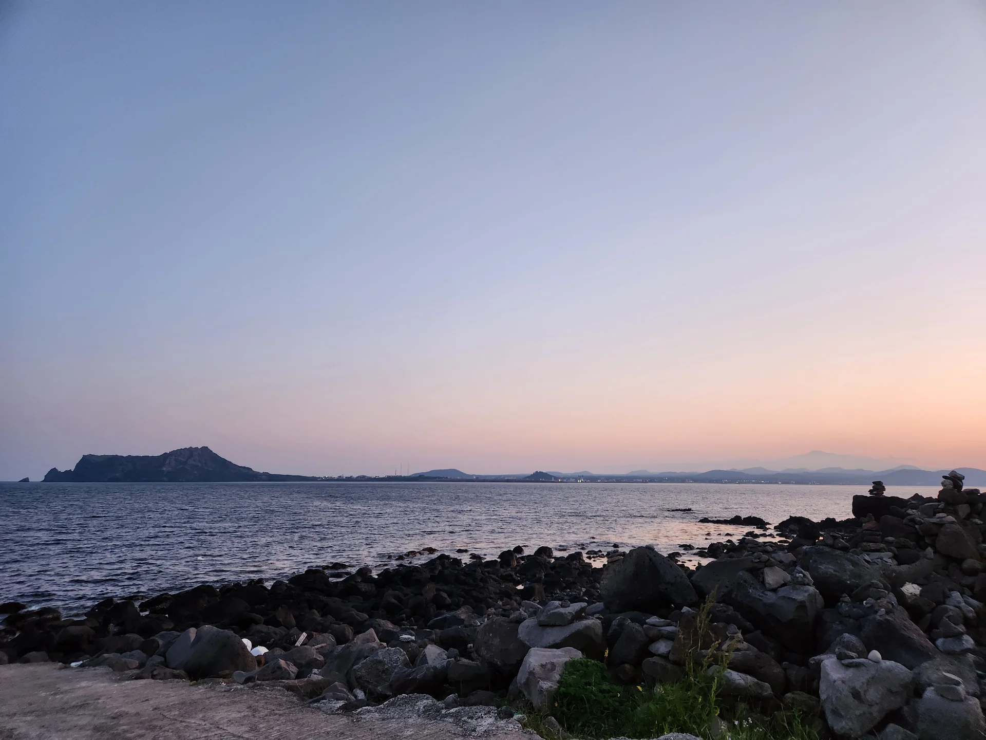 Bring the Korean coastline to your phone with these breathtaking ocean wallpapers. Korea is surrounded by water on three sides, and this collection captures it all — the turquoise shallows of Jeju's beaches, dramatic basalt cliffs plunging into the East Sea, tranquil fishing harbors at dawn, and endless Pacific horizons glowing under golden light.

These photos feature crashing waves against volcanic rock formations, serene island silhouettes at sunset, lighthouse beacons cutting through coastal fog, and the mirror-still surface of sheltered bays reflecting cotton-candy skies. Download these free Korean sea wallpapers for an aesthetic phone background that carries the calm and power of the ocean wherever you go., Udohaean-gil, Jeju — Free Korean aesthetic wallpaper