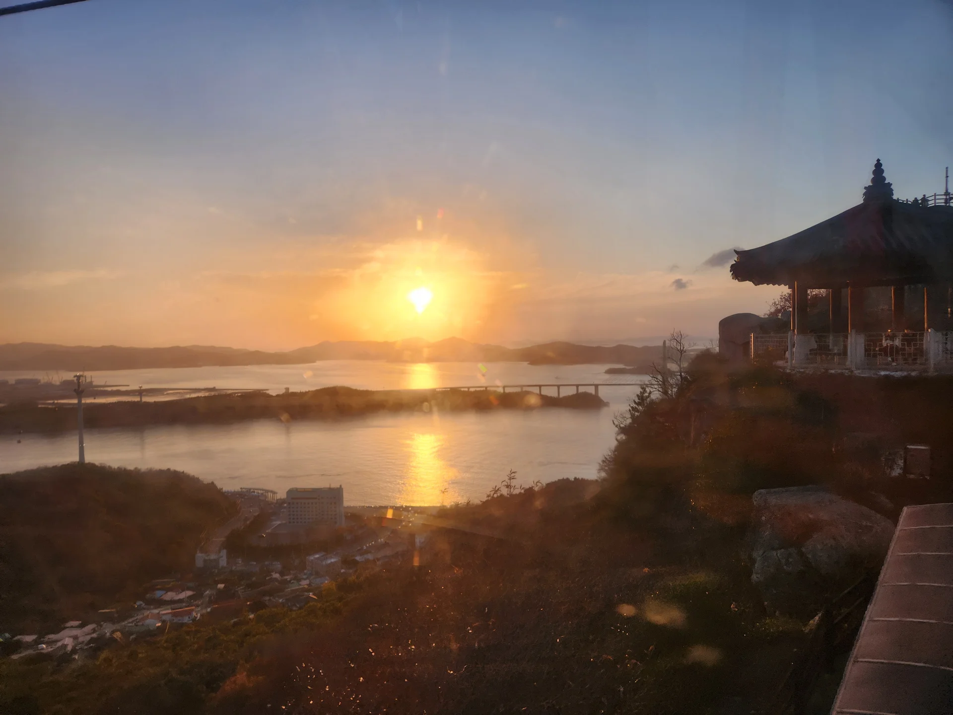 Paint your phone screen with the warm glow of a Korean sunset. These wallpapers capture golden hour at its most magical — amber light washing over temple rooftops, cotton-candy skies reflected in still rice paddies, and the Seoul skyline silhouetted against bands of pink, orange, and violet as the sun dips below the horizon.

Each image showcases a different face of the Korean evening: fishing boats returning to harbor under a fiery sky, lone hikers on ridgelines backlit by the last rays, and coastal cliffs glowing in warm light. These free aesthetic sunset wallpapers make the perfect phone background for anyone who wants a daily reminder of that peaceful, fleeting beauty between day and night., Mokpo-si, Jeollanam-do — Free Korean aesthetic wallpaper