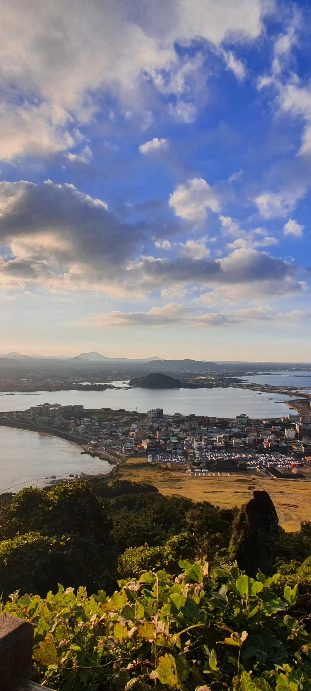 Paint your phone screen with the warm glow of a Korean sunset. These wallpapers capture golden hour at its most magical — amber light washing over temple rooftops, cotton-candy skies reflected in still rice paddies, and the Seoul skyline silhouetted against bands of pink, orange, and violet as the sun dips below the horizon.

Each image showcases a different face of the Korean evening: fishing boats returning to harbor under a fiery sky, lone hikers on ridgelines backlit by the last rays, and coastal cliffs glowing in warm light. These free aesthetic sunset wallpapers make the perfect phone background for anyone who wants a daily reminder of that peaceful, fleeting beauty between day and night., Jeju Island, Seongsan Ilchulbong — Free Korean aesthetic wallpaper