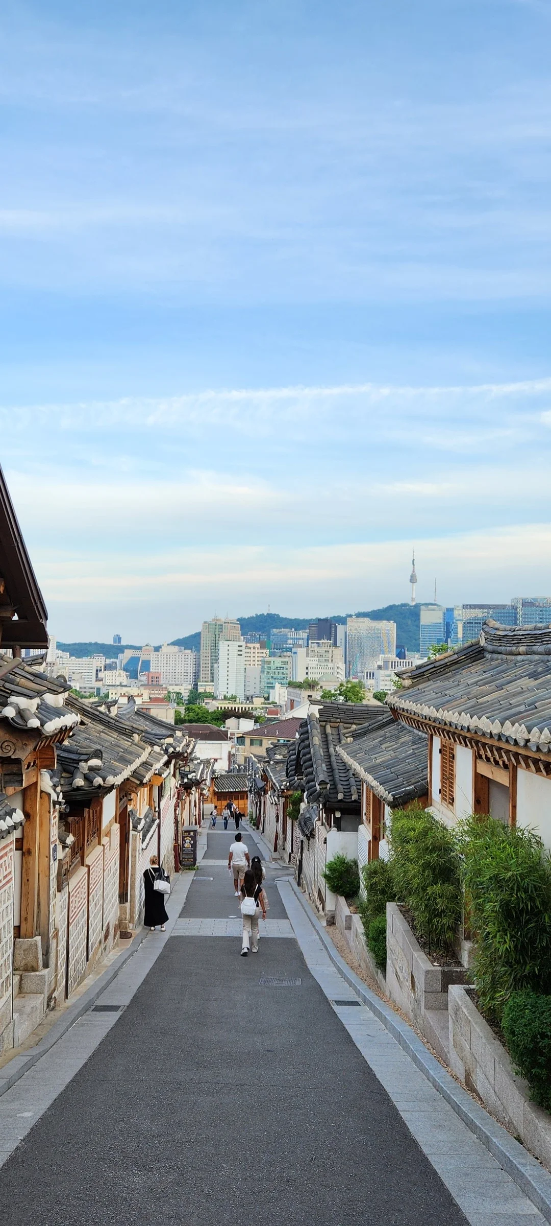 Experience the vibrant pulse of Korean city life through these dynamic street wallpapers. Bustling crosswalks in Myeongdong, colorful shop fronts in Hongdae, rain-slicked sidewalks reflecting neon signs, and everyday moments of commuters, street vendors, and cyclists moving through Seoul's urban rhythm — each image tells a story of a city constantly in motion.

Beyond Seoul, you'll find the charming streetscapes of Busan's hillside neighborhoods, the retro storefronts of Jeonju, and quiet residential lanes where laundry dries on balconies above parked scooters. These free Korean street wallpapers are perfect as an aesthetic phone background for anyone captivated by the raw energy and visual richness of Korean urban culture., 북촌로11나길, Gahoe-dong, Seoul — Free Korean aesthetic wallpaper