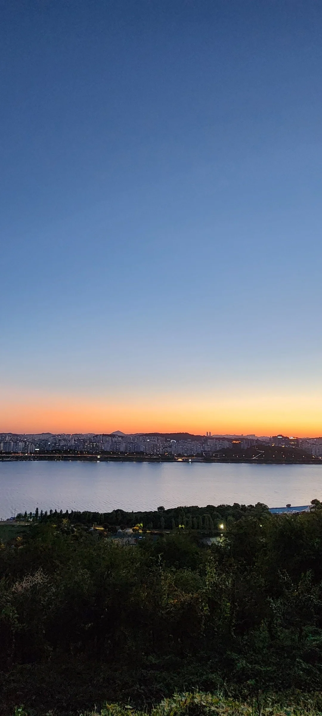 Light up your phone with the electric energy of Seoul after dark. These Korean nightscape wallpapers capture the city at its most cinematic — neon signage stacking up narrow alleyways, glowing street food stalls sending steam into cold night air, illuminated bridges spanning the Han River, and the shimmering towers of Gangnam reflected in rain-wet streets.

Seoul's nighttime personality is bold, colorful, and endlessly photogenic. You'll find the moody glow of Itaewon bars, the cyberpunk atmosphere of Euljiro's industrial blocks, and panoramic cityscapes from hilltop viewpoints where the city stretches to the horizon in every direction. Free download these aesthetic Seoul night wallpapers for a phone background that pulses with urban energy., Gangbyeonbuk-ro, Sangam-dong, Seoul — Free Korean aesthetic wallpaper