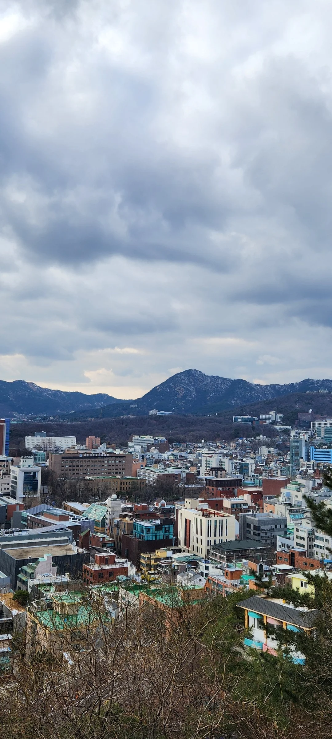Experience the vibrant pulse of Korean city life through these dynamic street wallpapers. Bustling crosswalks in Myeongdong, colorful shop fronts in Hongdae, rain-slicked sidewalks reflecting neon signs, and everyday moments of commuters, street vendors, and cyclists moving through Seoul's urban rhythm — each image tells a story of a city constantly in motion.

Beyond Seoul, you'll find the charming streetscapes of Busan's hillside neighborhoods, the retro storefronts of Jeonju, and quiet residential lanes where laundry dries on balconies above parked scooters. These free Korean street wallpapers are perfect as an aesthetic phone background for anyone captivated by the raw energy and visual richness of Korean urban culture., Naksan 4-gil, Ihwa-dong, Seoul — Free Korean aesthetic wallpaper