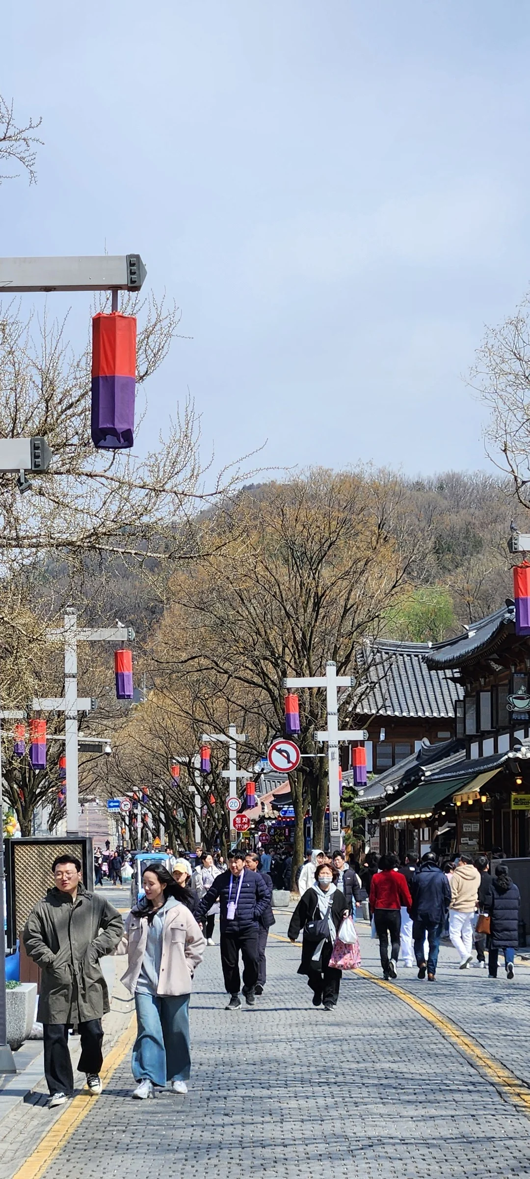 Experience the vibrant pulse of Korean city life through these dynamic street wallpapers. Bustling crosswalks in Myeongdong, colorful shop fronts in Hongdae, rain-slicked sidewalks reflecting neon signs, and everyday moments of commuters, street vendors, and cyclists moving through Seoul's urban rhythm — each image tells a story of a city constantly in motion.

Beyond Seoul, you'll find the charming streetscapes of Busan's hillside neighborhoods, the retro storefronts of Jeonju, and quiet residential lanes where laundry dries on balconies above parked scooters. These free Korean street wallpapers are perfect as an aesthetic phone background for anyone captivated by the raw energy and visual richness of Korean urban culture., Taejo-ro, Jeon-dong, Jeonju-si — Free Korean aesthetic wallpaper