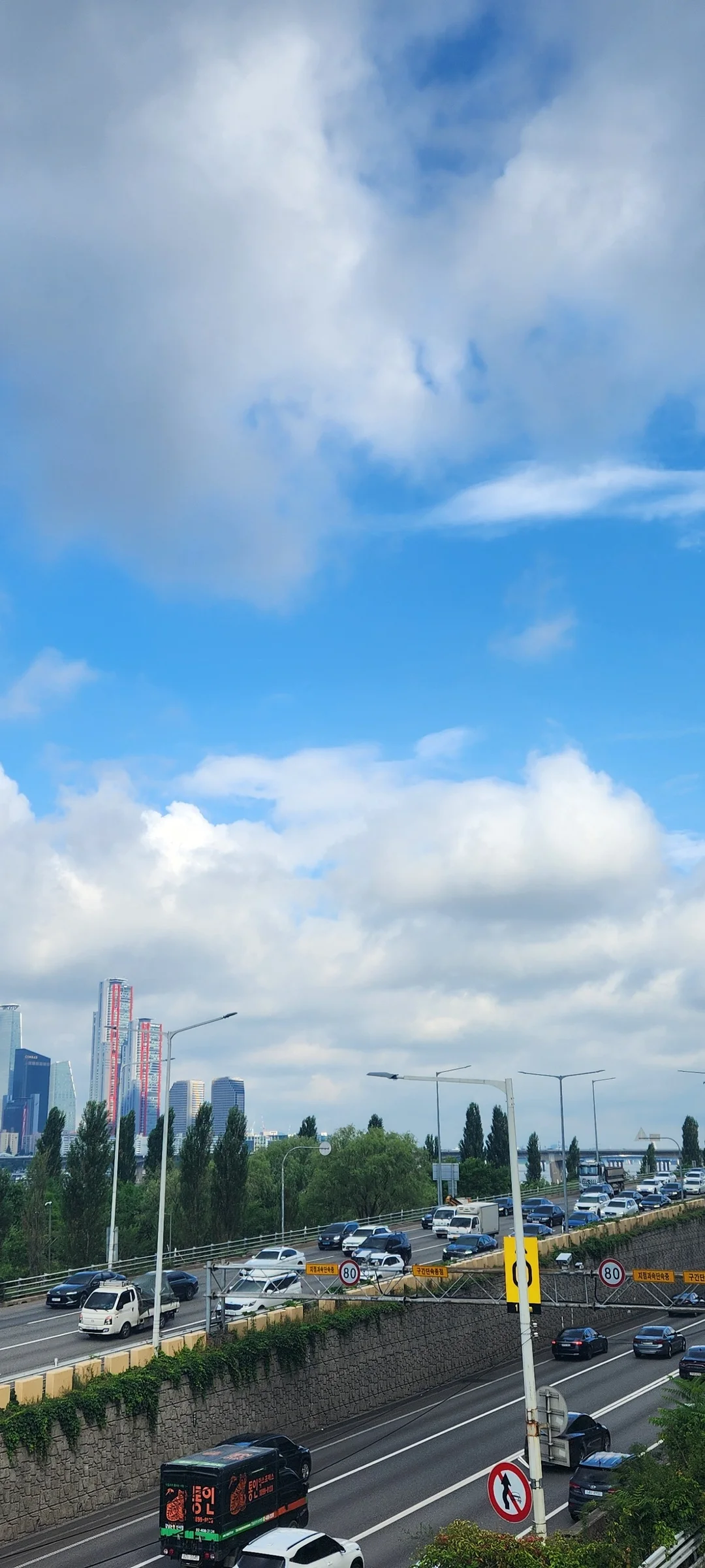 Experience the vibrant pulse of Korean city life through these dynamic street wallpapers. Bustling crosswalks in Myeongdong, colorful shop fronts in Hongdae, rain-slicked sidewalks reflecting neon signs, and everyday moments of commuters, street vendors, and cyclists moving through Seoul's urban rhythm — each image tells a story of a city constantly in motion.

Beyond Seoul, you'll find the charming streetscapes of Busan's hillside neighborhoods, the retro storefronts of Jeonju, and quiet residential lanes where laundry dries on balconies above parked scooters. These free Korean street wallpapers are perfect as an aesthetic phone background for anyone captivated by the raw energy and visual richness of Korean urban culture., Ichon-ro, Ichon 2(i)-dong, Seoul — Free Korean aesthetic wallpaper