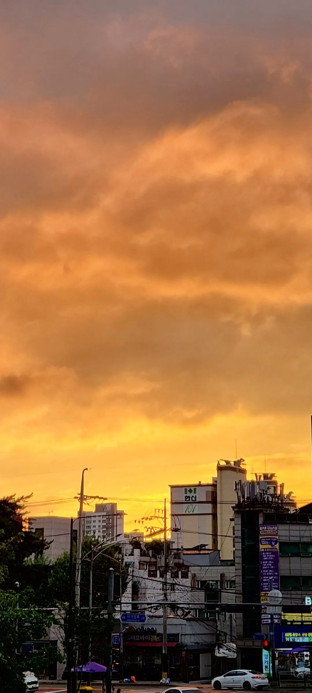 Paint your phone screen with the warm glow of a Korean sunset. These wallpapers capture golden hour at its most magical — amber light washing over temple rooftops, cotton-candy skies reflected in still rice paddies, and the Seoul skyline silhouetted against bands of pink, orange, and violet as the sun dips below the horizon.

Each image showcases a different face of the Korean evening: fishing boats returning to harbor under a fiery sky, lone hikers on ridgelines backlit by the last rays, and coastal cliffs glowing in warm light. These free aesthetic sunset wallpapers make the perfect phone background for anyone who wants a daily reminder of that peaceful, fleeting beauty between day and night., Dapsimni-ro, Dapsimni 1(il)-dong, Seoul — Free Korean aesthetic wallpaper