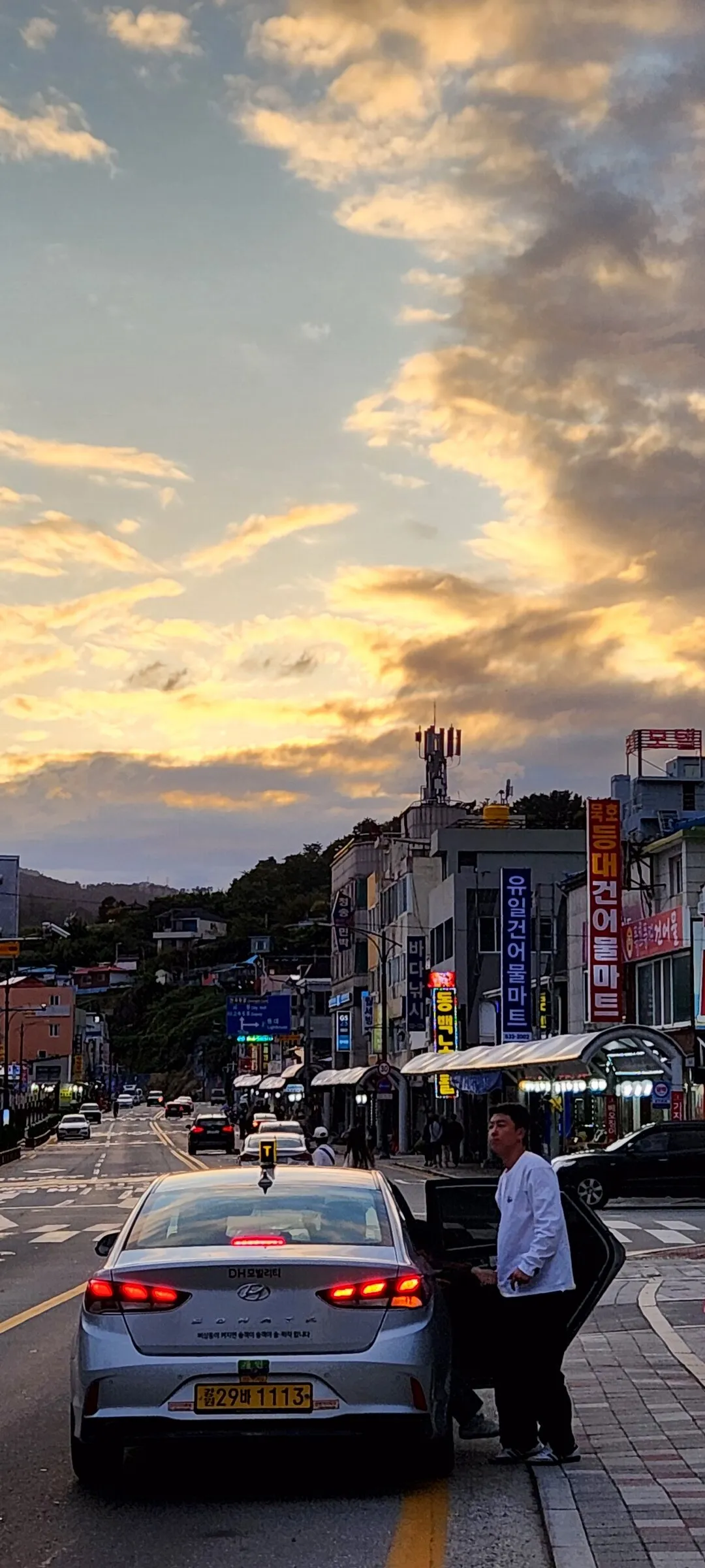 Experience the vibrant pulse of Korean city life through these dynamic street wallpapers. Bustling crosswalks in Myeongdong, colorful shop fronts in Hongdae, rain-slicked sidewalks reflecting neon signs, and everyday moments of commuters, street vendors, and cyclists moving through Seoul's urban rhythm — each image tells a story of a city constantly in motion.

Beyond Seoul, you'll find the charming streetscapes of Busan's hillside neighborhoods, the retro storefronts of Jeonju, and quiet residential lanes where laundry dries on balconies above parked scooters. These free Korean street wallpapers are perfect as an aesthetic phone background for anyone captivated by the raw energy and visual richness of Korean urban culture., Ilchul-ro, Mukho-dong, Donghae-si — Free Korean aesthetic wallpaper